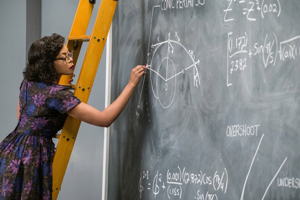 Scene from the movie "Hidden Figures" showing Taraji P. Henson's character standing on a ladder and working out a mathematic formula on a chalkboard. She's wearing glasses and a '60s-era dress.