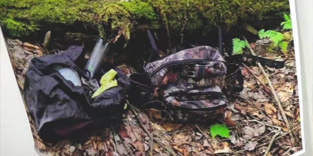 Camo bags and other supplies hidden under a mossy log in the woods of Pennsylvania