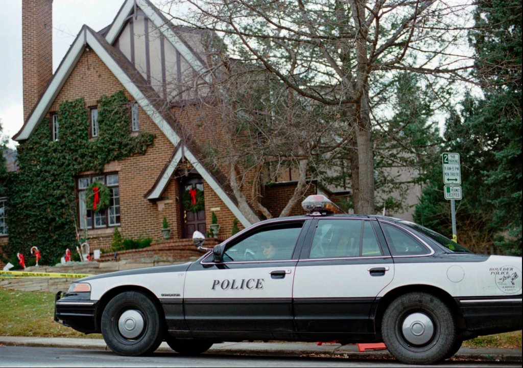 A Boulder police officer sits in a patrol car outside of the Ramsey home.