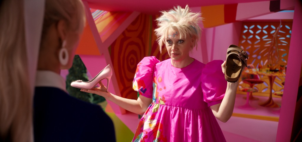 Kate McKinnon with chopped blond hair in a "Barbie" movie still. 