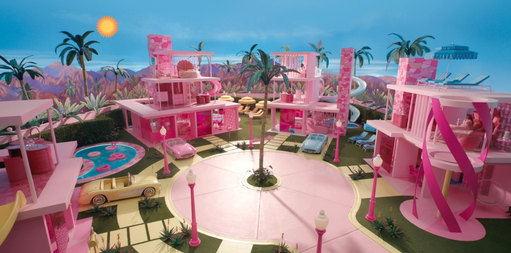 A still from the "Barbie" movie showing various pink Barbie dream homes with waterslides. 