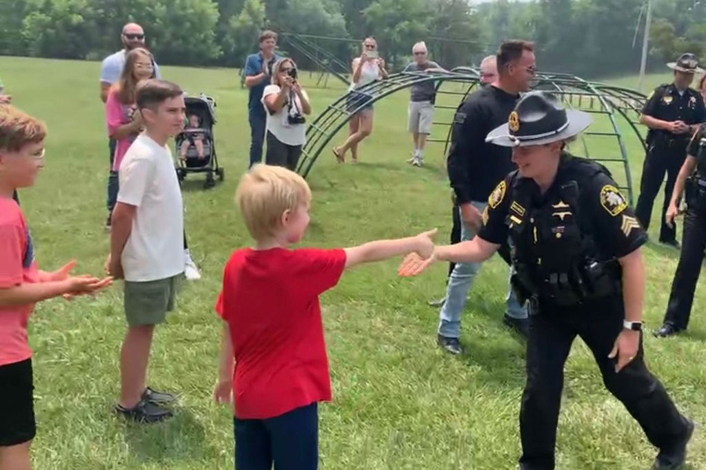 7-year-old Griffin shakes the hand of a sheriff at an outdoor event.