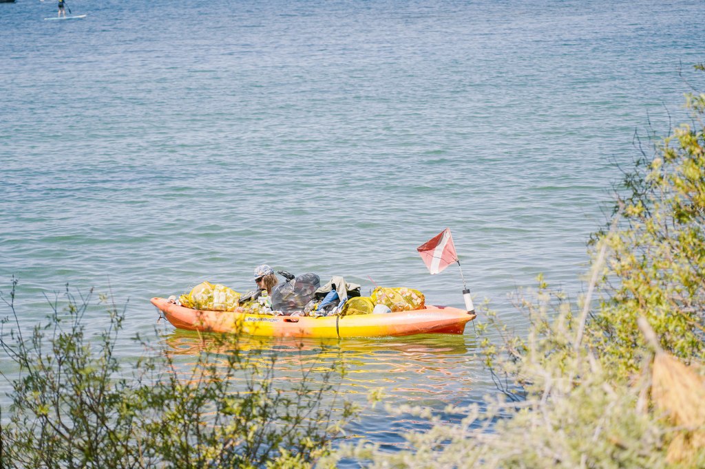 A kayaker reaches for the trash.