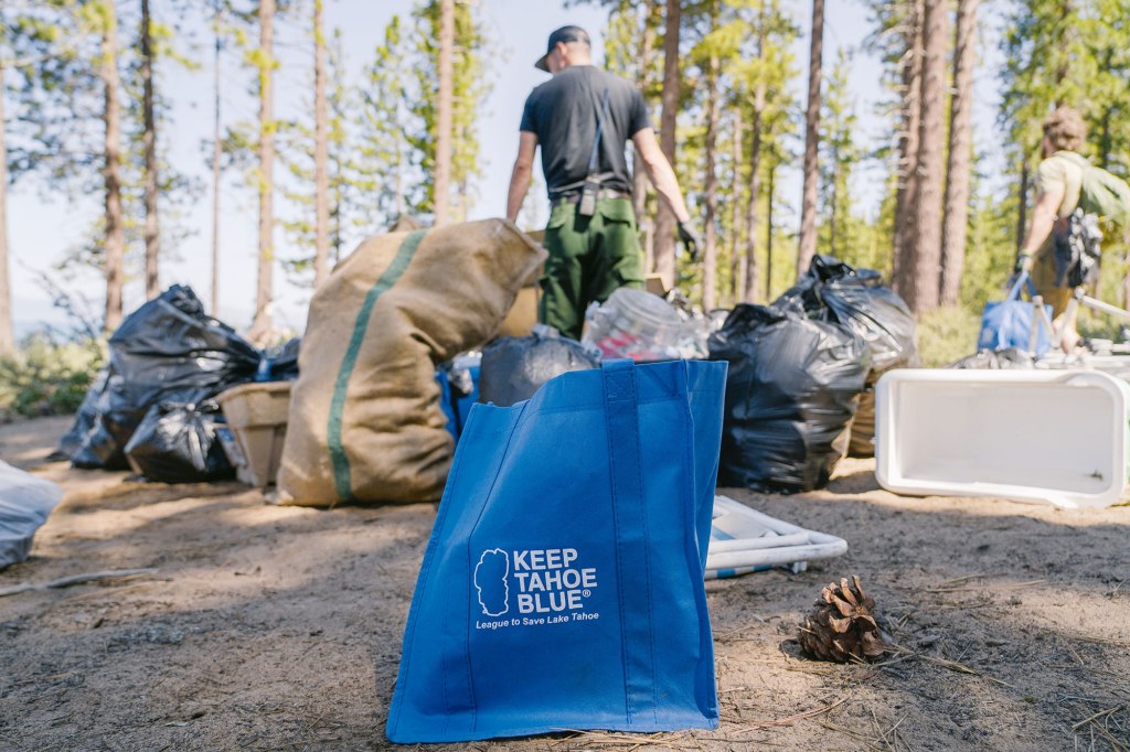 A volunteer fills a bag of trash.