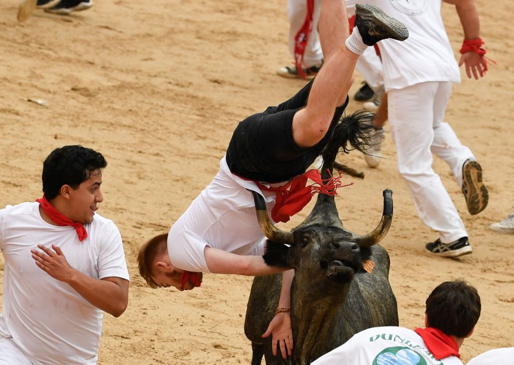 A man getting flipped over by a charging bull.