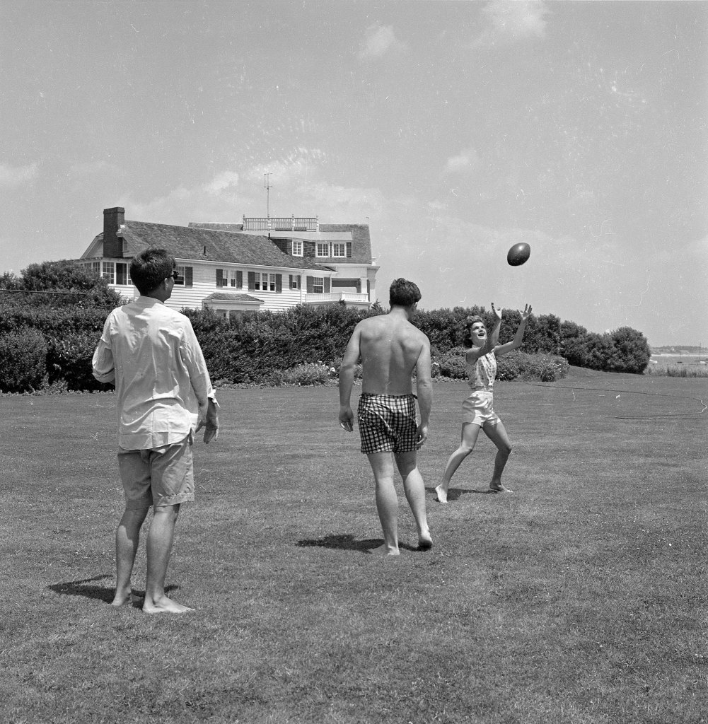 A newly engaged Senator John F. Kennedy playing touch football on the lawn in 1953 with Jacqueline Bouvier and his brother Edward. 