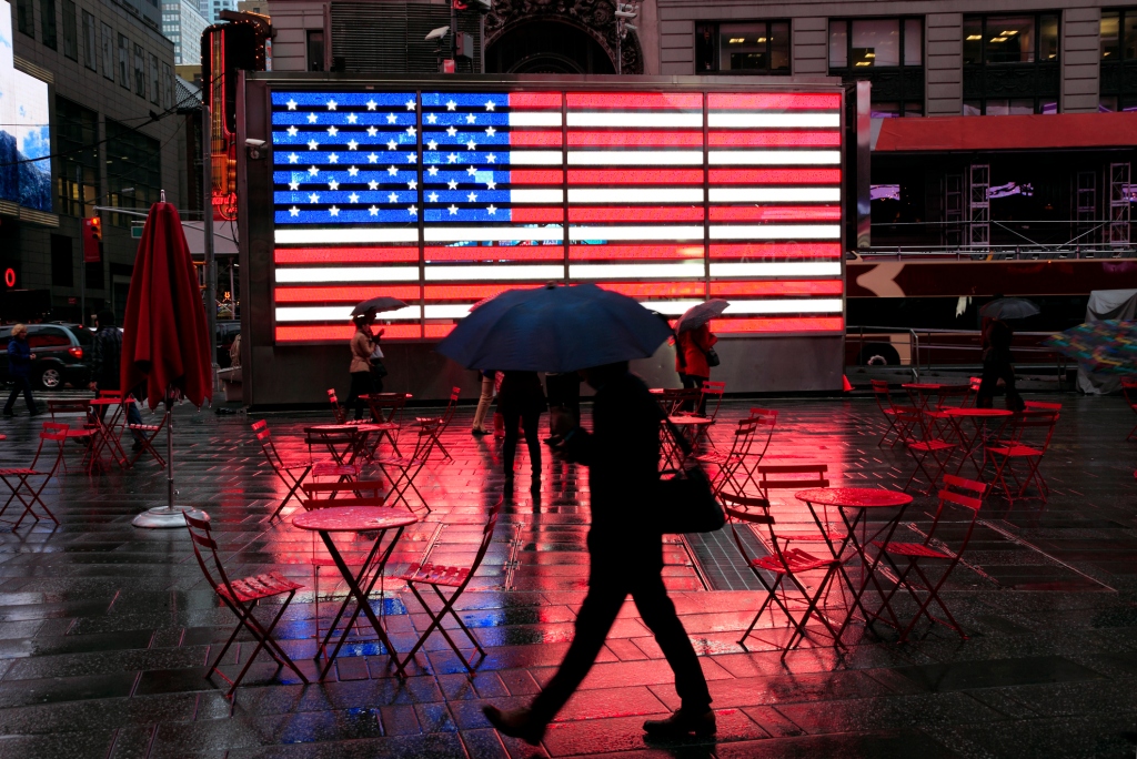 A person with an umbrella walks through the rain in Times Square.