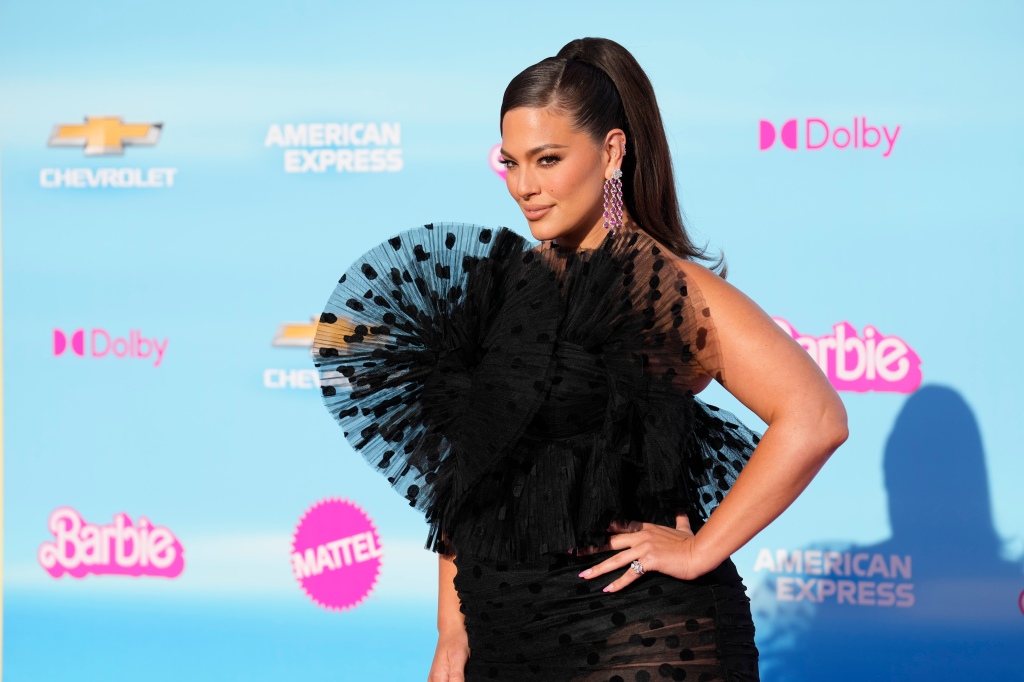 Ashley Graham in a black feathered dress on a red carpet. 