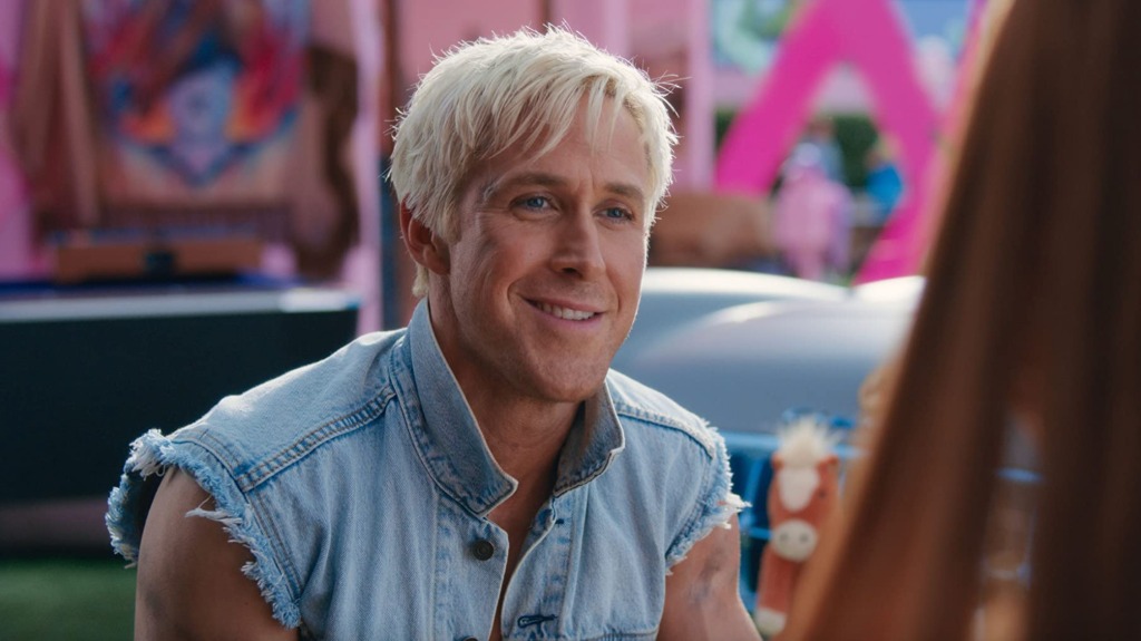 Ken wears a denim vest and smiles at an off-screen Barbie. 