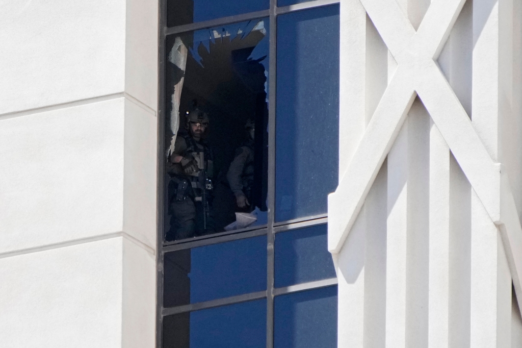 A police officer looks out of a broken window on a hotel tower at Caesars Palace 