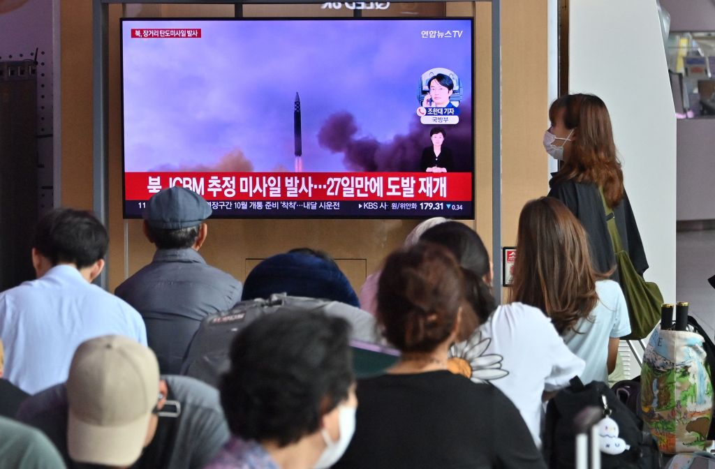 People watch a television screen showing a news broadcast with footage of a North Korean missile test, at a railway station in Seoul on July 12, 2023.