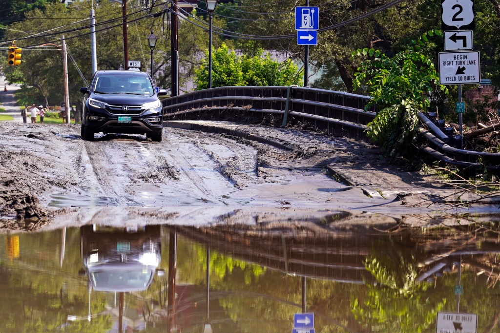 A driver stops on a mud-covered bridge while deciding whether to drive through flood waters of the Winooski River, Wednesday, July 12, 2023, in Montpelier, Vt.
