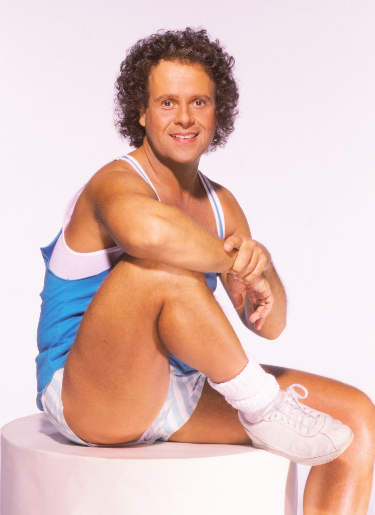 Richard Simmons in 1992 smiling and dressed in a tank top and shorts. 