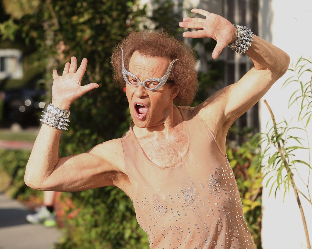 Richard Simmons in a sparkly tank top, a bracelet, and sparkly glasses. 