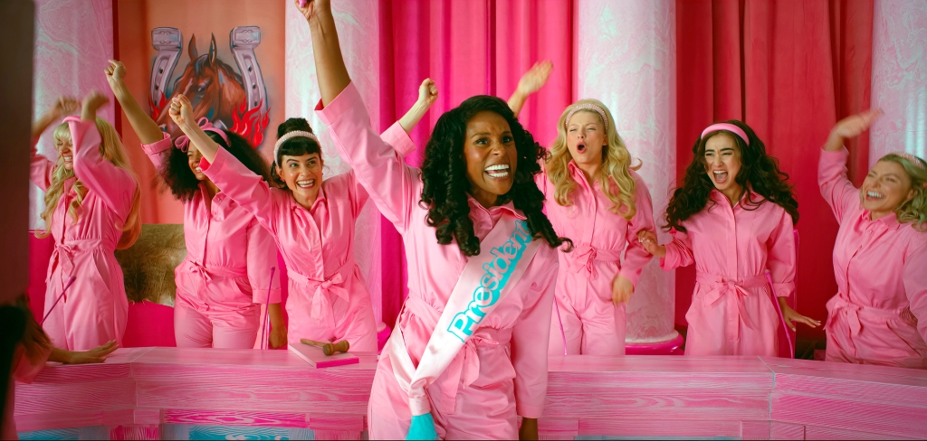 Still from "Barbie" movie with Issa Rae front and center and other Barbies behind her. 