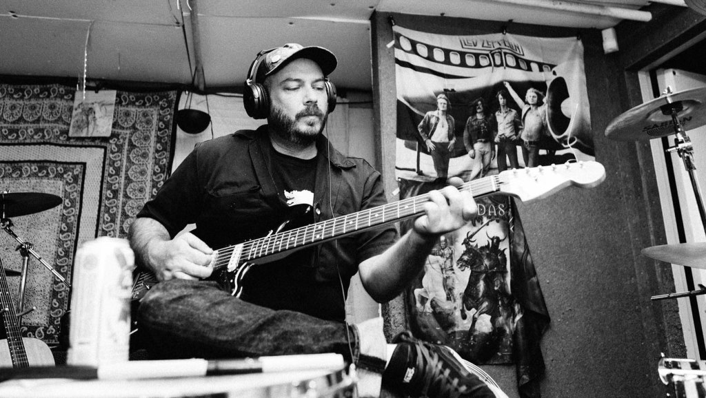 An undated photo of Christensen playing guitar and singing in a home studio. 