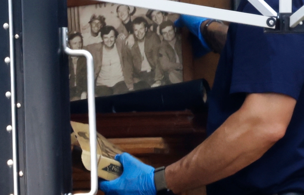 SI looking at a photo of the cast from the show MASH, part of the items that were removed from the home of Rex Heuermann