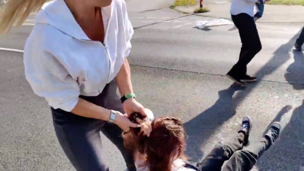Woman dragging activist by the hair.
