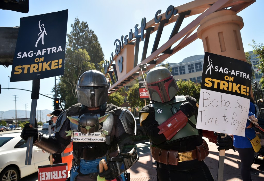 Tim Brehmer, left, and a fellow picketer dress as characters from "The Mandalorian" outside Disney studios on Thursday, July 20, 2023, in Burbank, Calif.