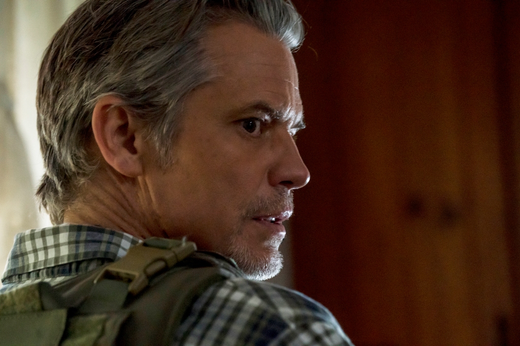 Timothy Olyphant with his face turned to the side looking serious. 