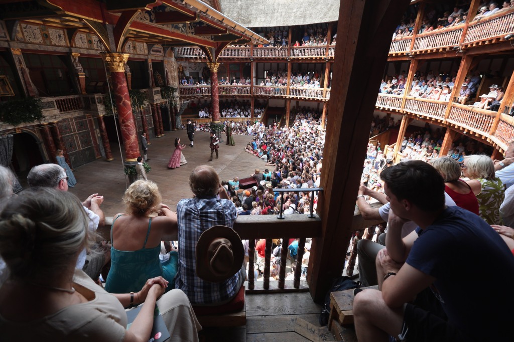 Audience members watch a production  in Shakespeare's Globe theatre.