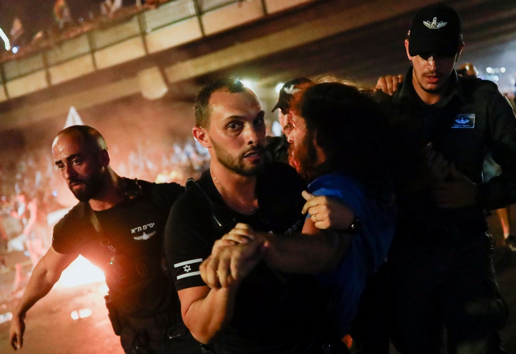 Police detain a person as protesters block Ayalon Highway during a demonstration following the parliament vote.