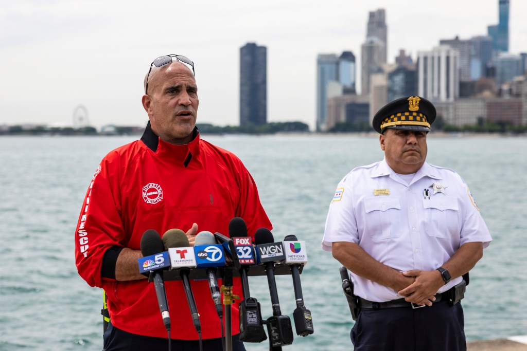 Chicago Police Department Lt. Jose Mendez looks on while Chicago Fire Department Deputy District Chief Jason Lach talks about the deadly crash.