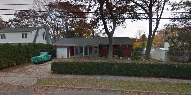 Red house with wrapped up car in driveway and leaves falling