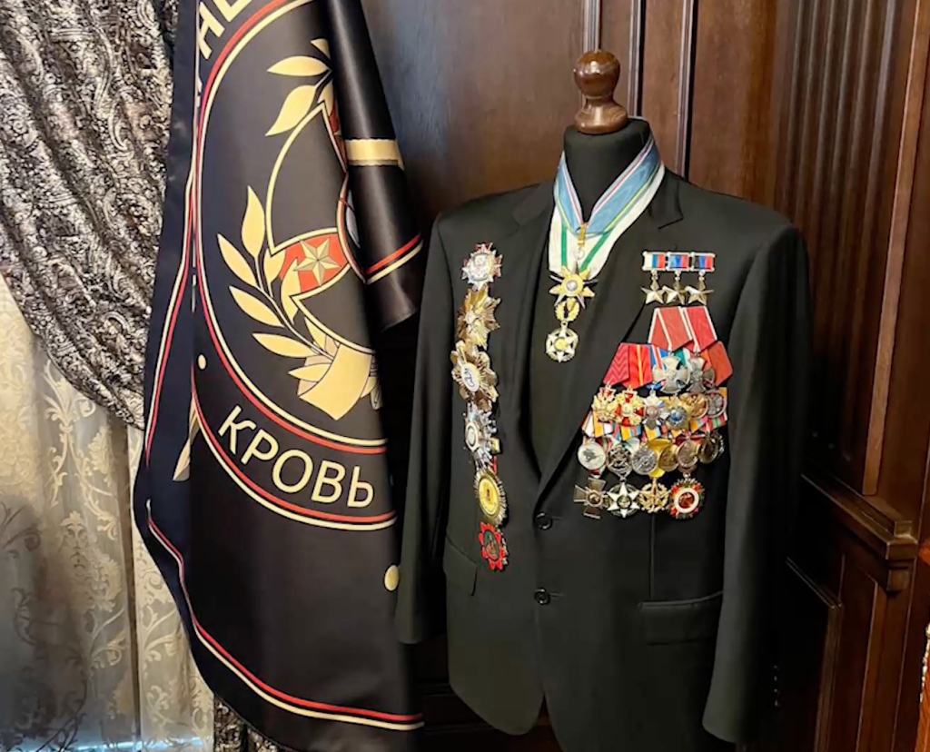 A suit decorated with various medals was found next to a flag that reads "blood" in Russian. 