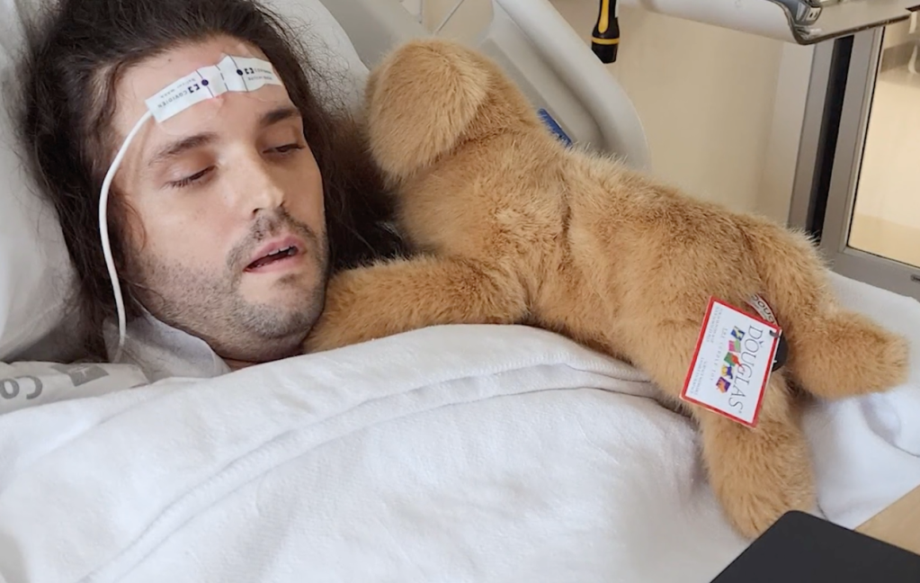 Michael lies down in the hospital with a stuffed dog