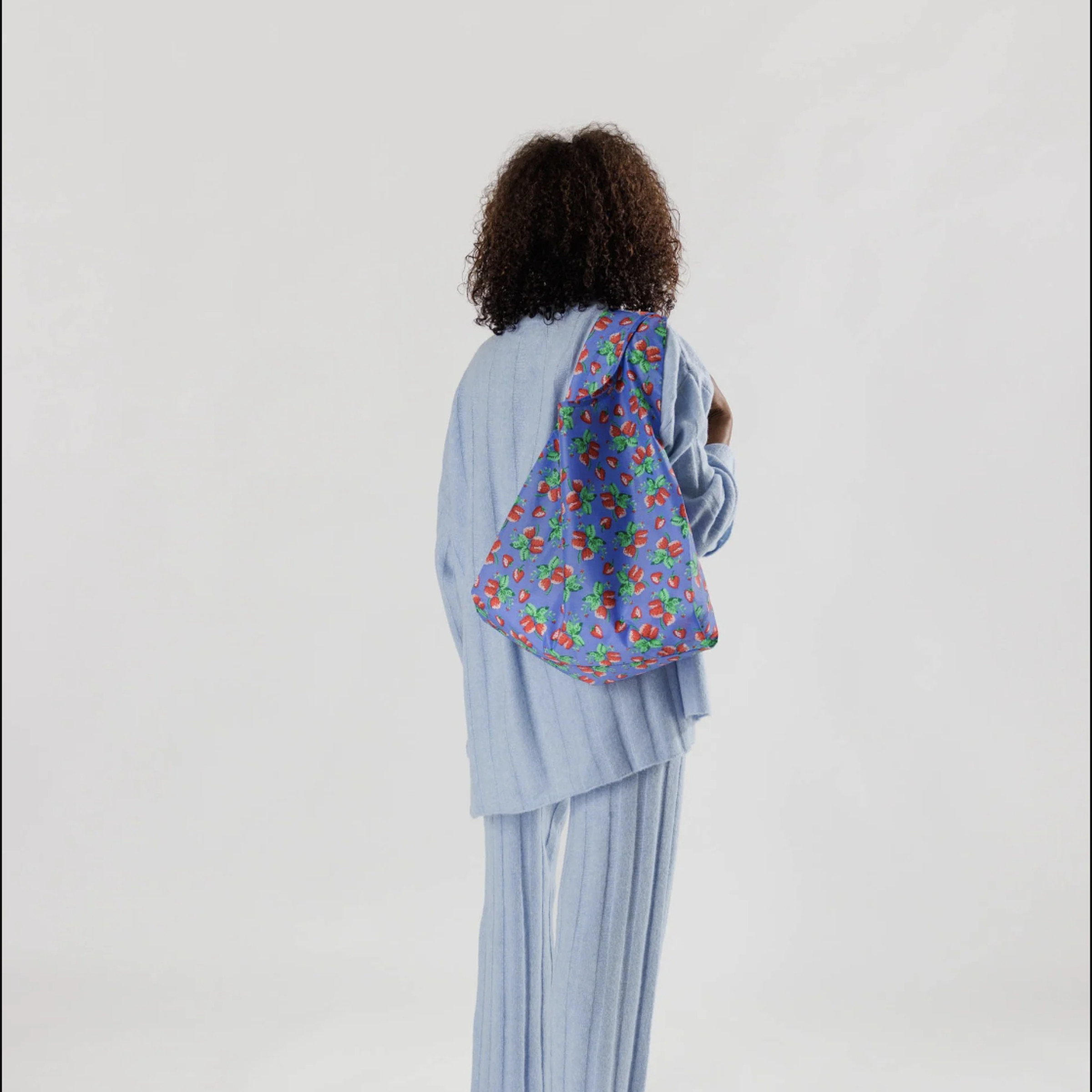 Woman carrying flowered bag over one shoulder.