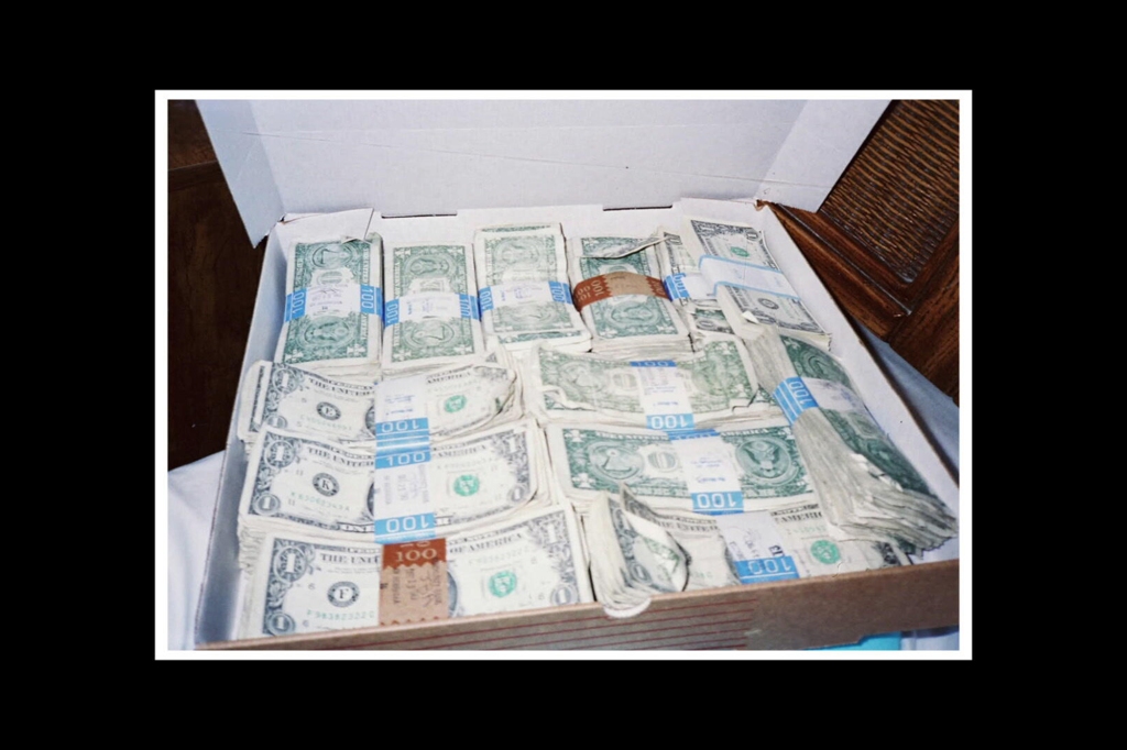 Photo showing stacks of $100 dollar US bills sitting in a cardboard box.
