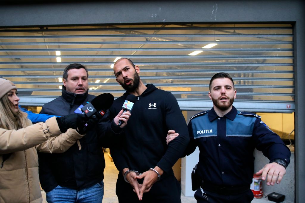 Tate (C) speaks to media while being escorted by police officers after being questioned at the Directorate for Investigating Organized Crime and Terrorism (DIICOT) in Bucharest, Romania, 25 January 2023.