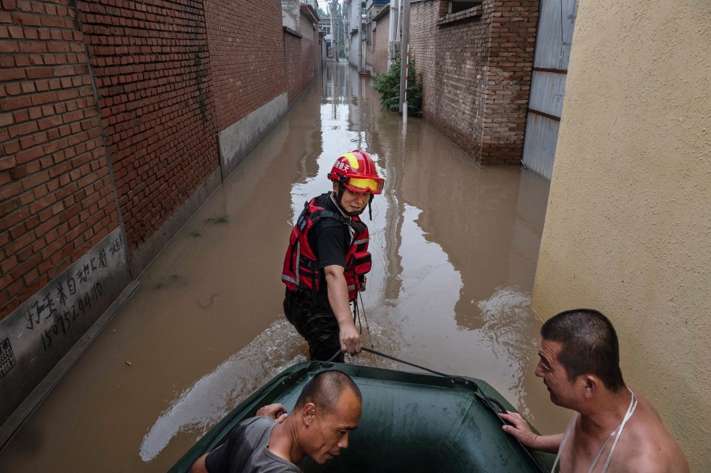 A rescue worker pulls a boat carrying local residents being helped to safety in an area inundated with floodwaters on Aug. 3, 2023 near Zhuozhou, Hebei Province south of Beijing, China. 