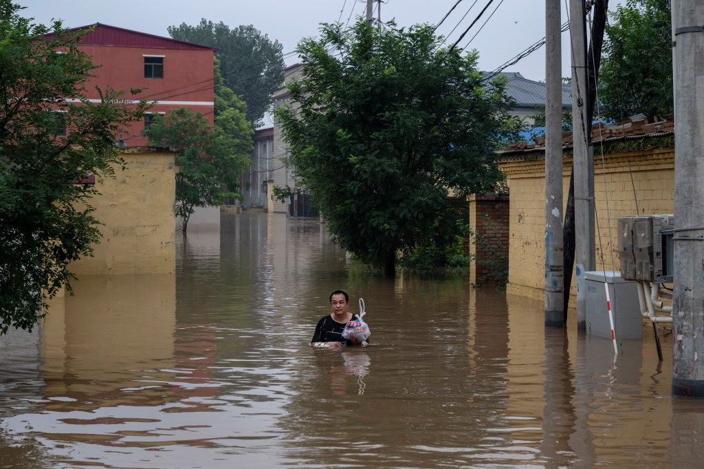 A local resident wades in chest deep floodwaters towards a rescue boat to be helped to safety in an area inundated with floodwaters on Aug. 3, 2023 near Zhuozhou, Hebei Province south of Beijing, China. 