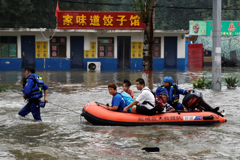 Rescue workers from Shanxi province evacuate people through floodwaters with a boat after the rains and floods brought by remnants of Typhoon Doksuri, in Zhuozhou, Hebei province, China on Aug. 3, 2023. 