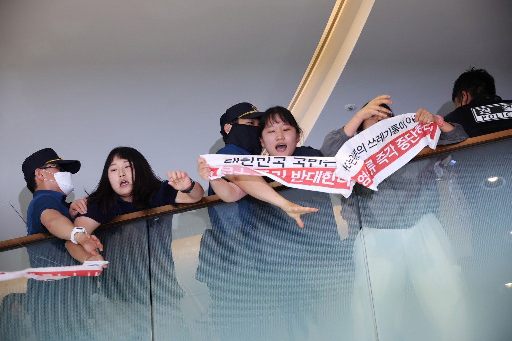 The group was able to reach the eighth floor, where the embassy in located, hanging banners condemning the release on Aug. 24, 2023, in Seoul. 
