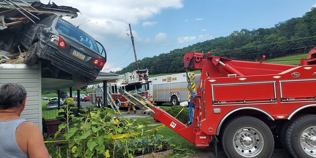 Car being towed from second floor roof area of home