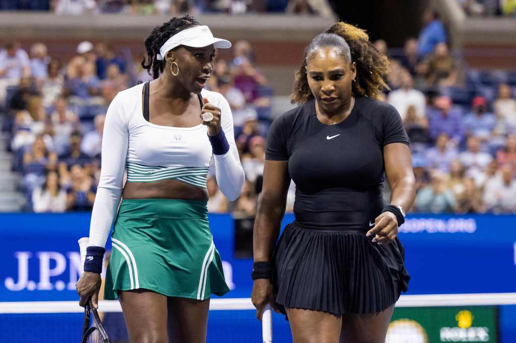 Serena Williams (R) and Venus Williams talk to each other in the middle of their women's doubles first round match at the US Open tournament on Sept. 1, 2022 in Queens.