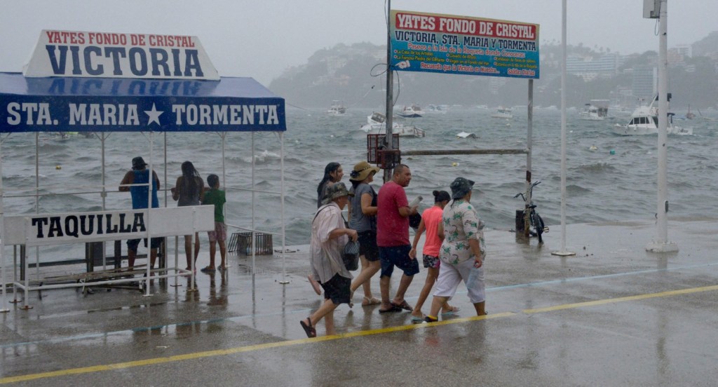 People walk along the coast in Acapulco, Guerrero State, Mexico, on Aug. 16, 2023, following the passage of Tropical Storm Hilary. (Photo by FRANCISCO ROBLES / AFP) (Photo by FRANCISCO ROBLES/AFP via Getty Images)