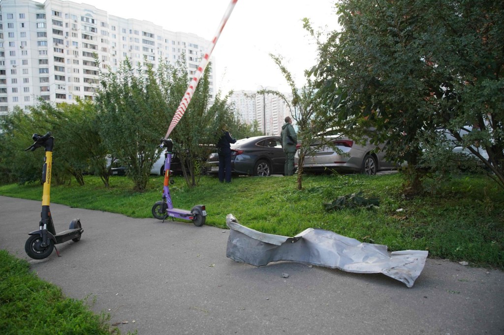 Local residents stand next to debris following the drone attack in Krasnogorsk on Aug. 2, 2023. 