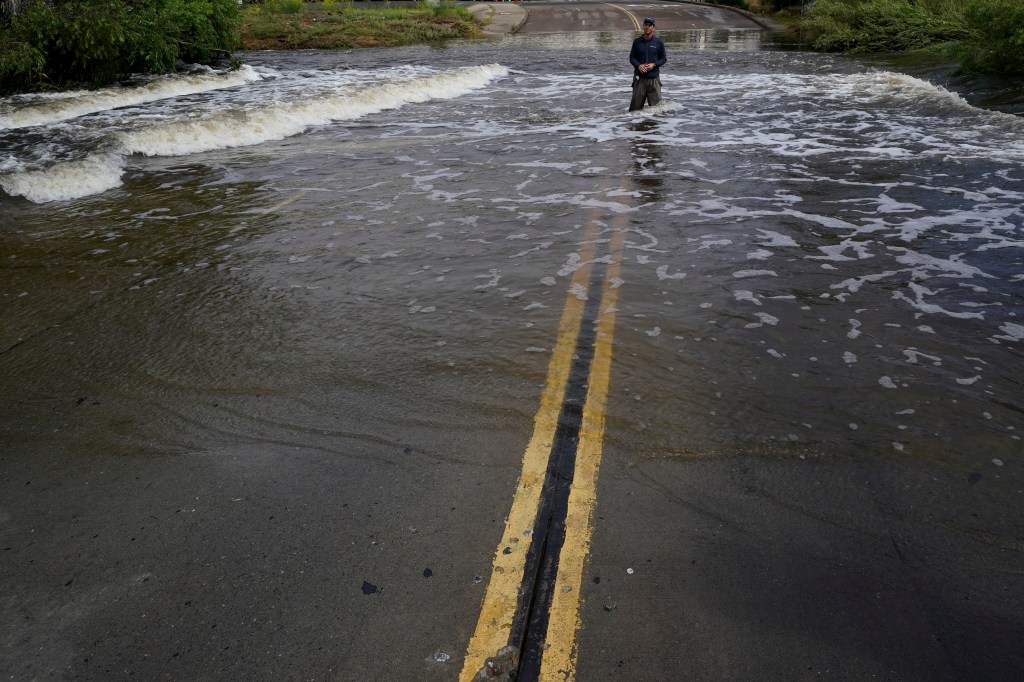 A television reporter stands in a flooded road after the passing of Tropical Storm Hilary, on Aug. 21, 2023, in San Diego.