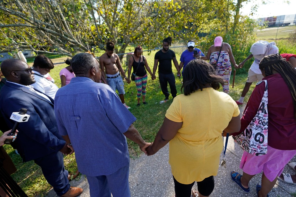 Residents holding hands as they pray near the scene of the shooting.