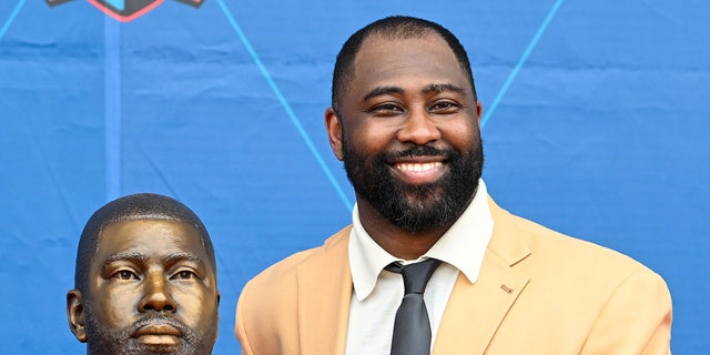 Darrelle Revis smiles next to bust