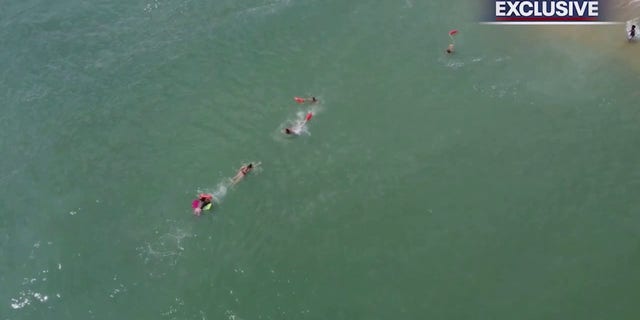 lifeguards swimming to boogie boarder