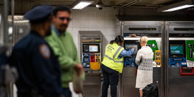 An MTA worker helps a commuter