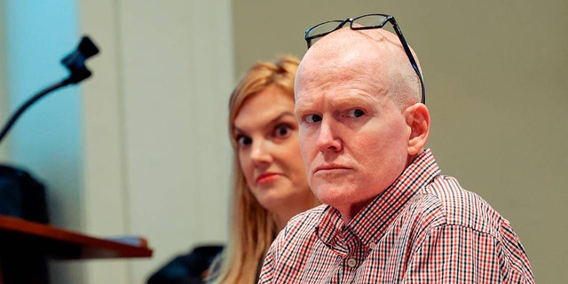 a close-up of the bald Alex Murdaugh in sitting in court with a plaid shirt next to his legal team