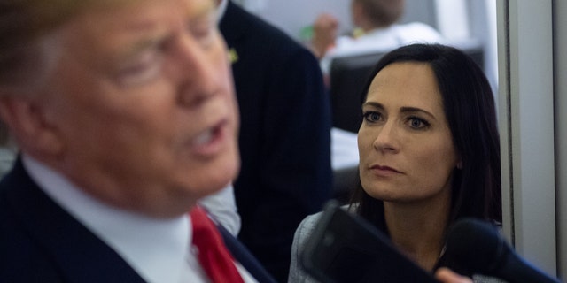 White House Press Secretary Stephanie Grisham listens as President Donald Trump speaks