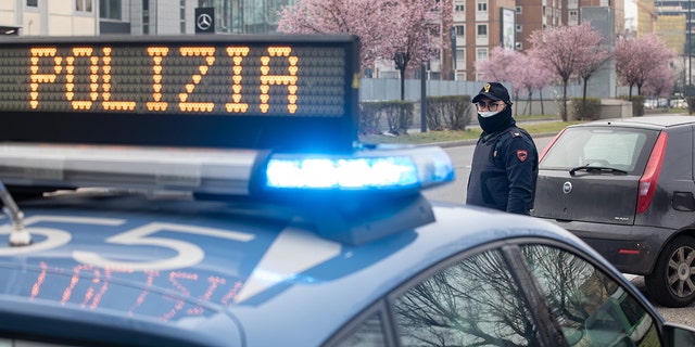 Italian police officer stands outside a police car