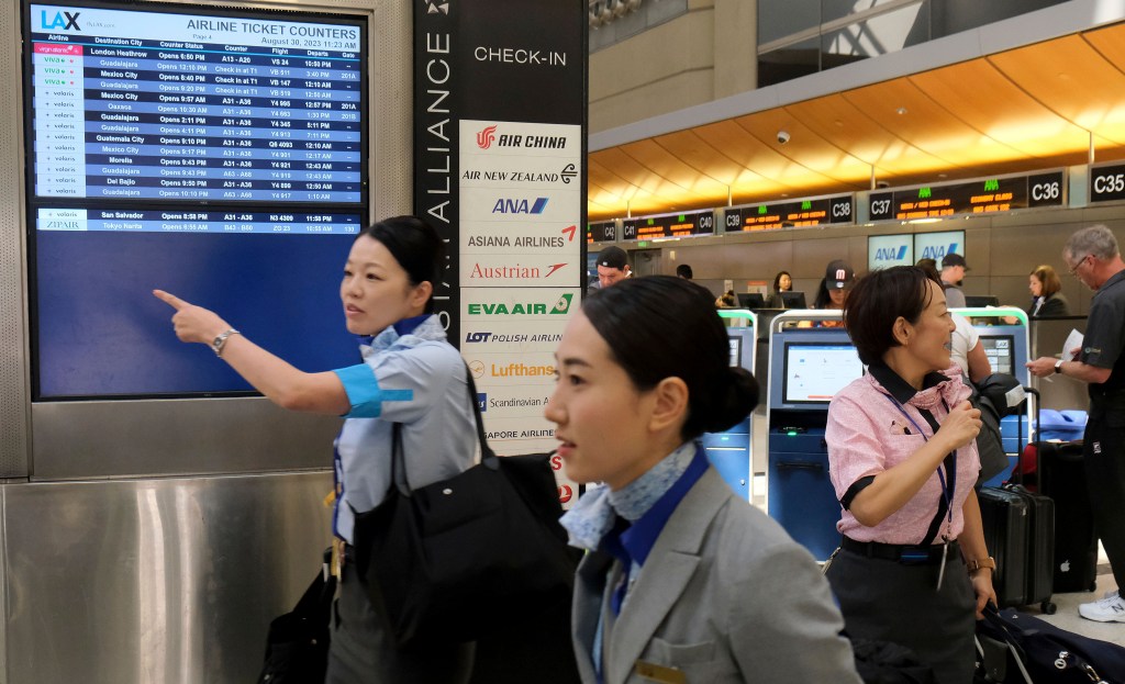 Flight attendants and travelers make their way through the Tom Bradley International Terminal at LAX on Aug. 30, 2023, in Los Angeles. 